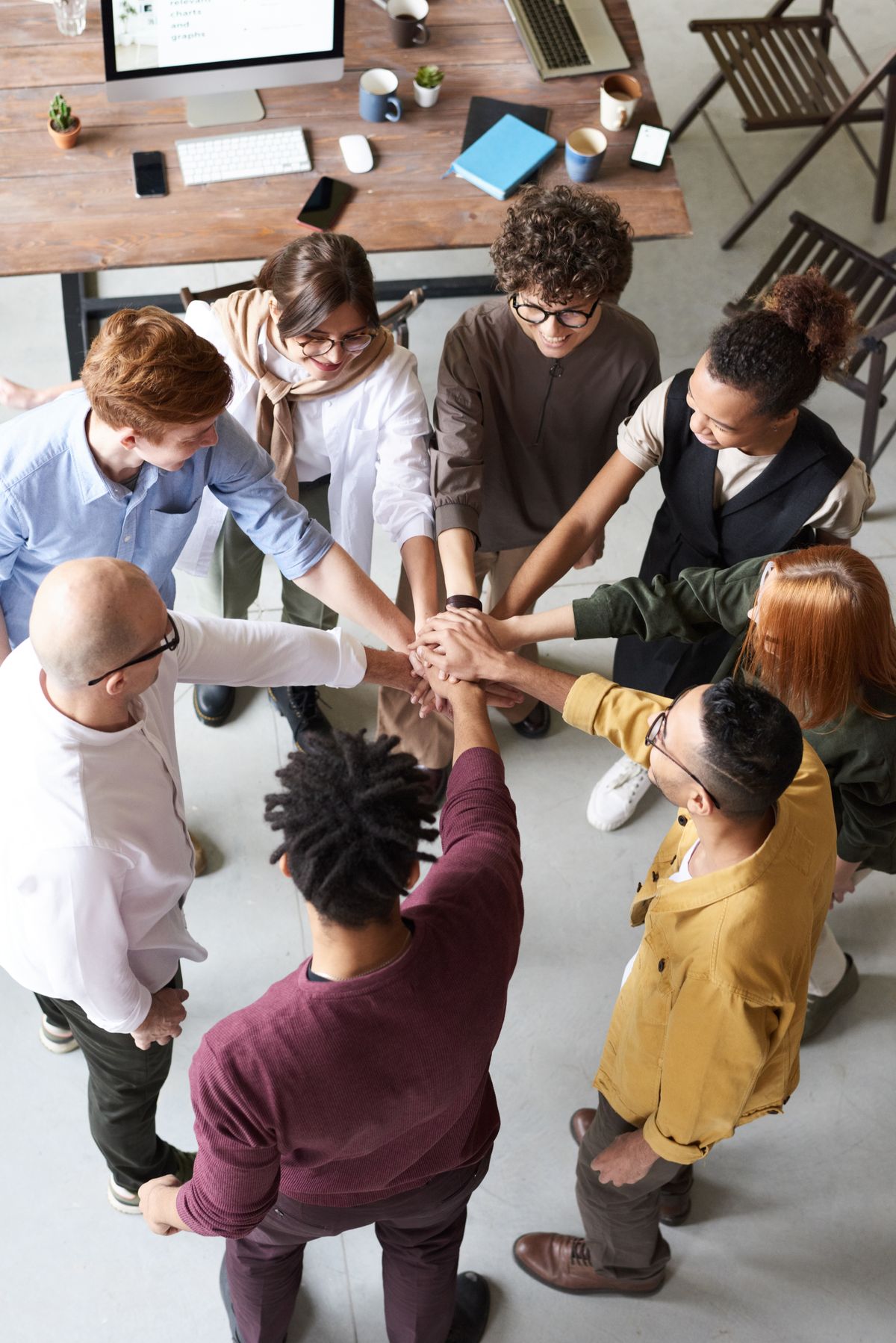 Colleagues bringing their hands together over a meeting table