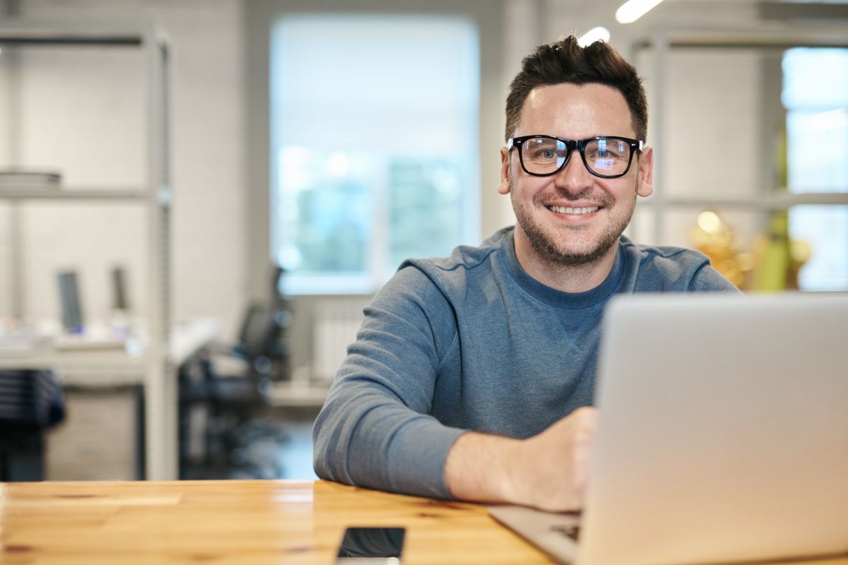 A smiling business owner seated at his laptop