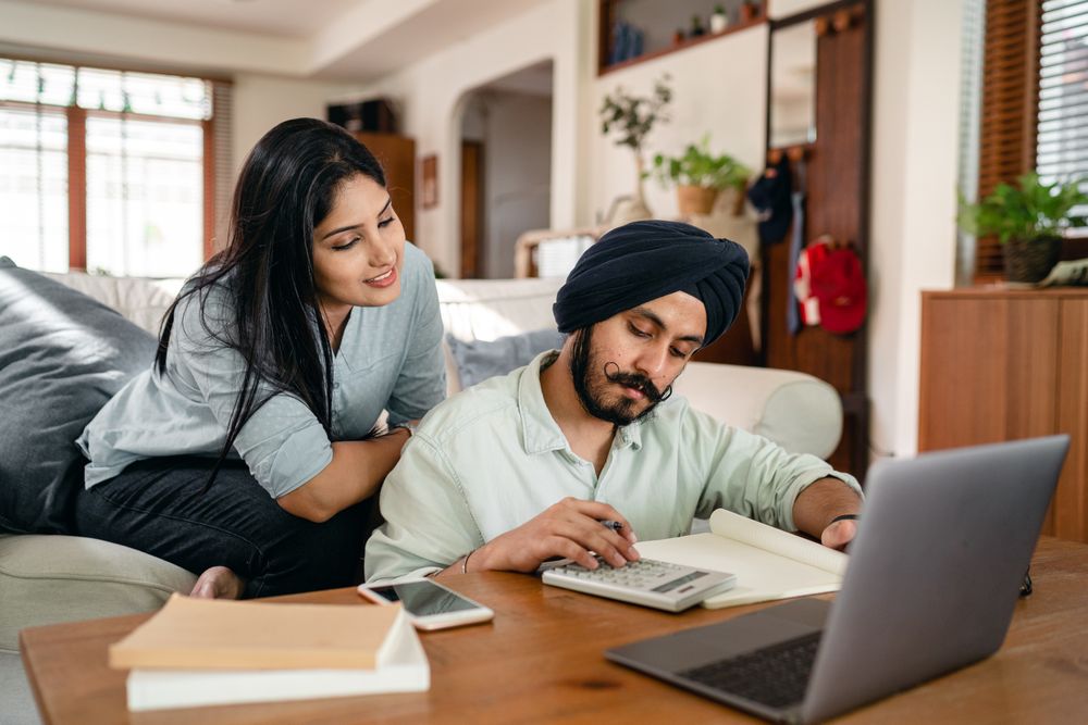 Two people reconciling records with a calculator and laptop